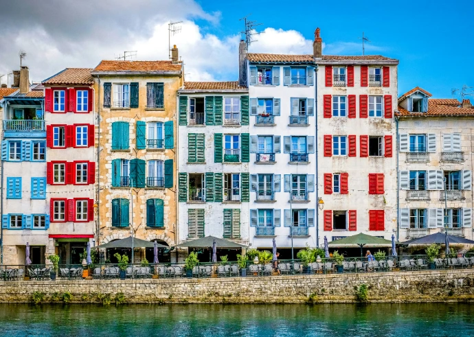 Colorful buildings line a river under a sunny sky.